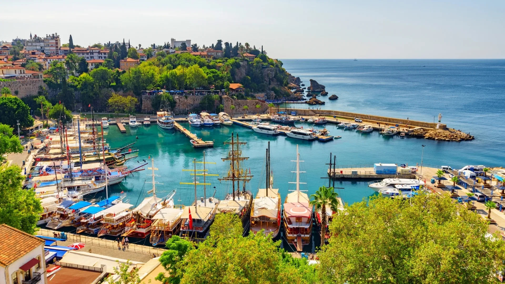 Antalya Old Harbor with traditional boats, turquoise waters, and historic city views from above.
