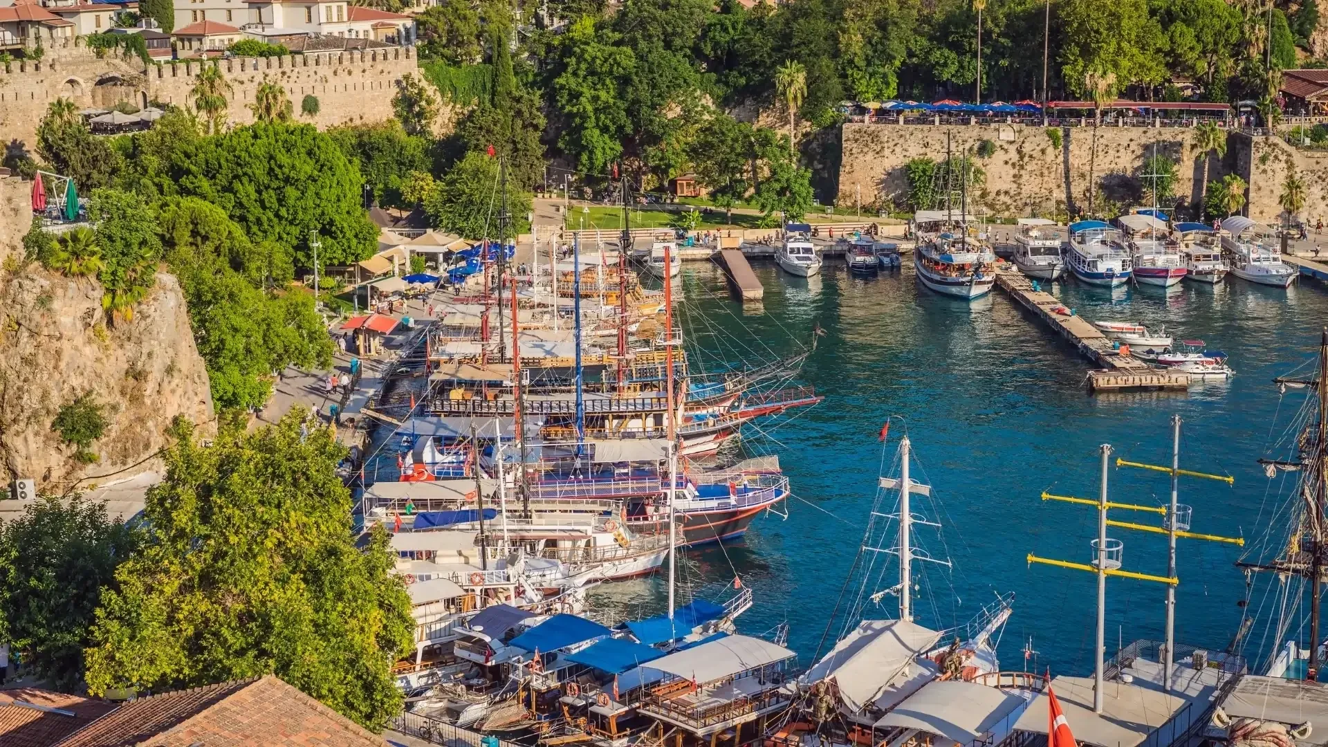 Antalya Old Harbor with traditional boats, turquoise waters, and historic city views from above.